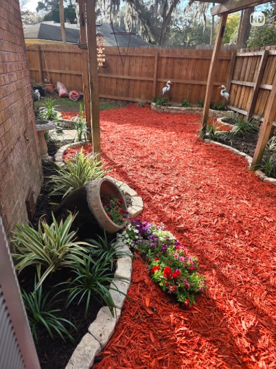 Boardman Lawncare red mulch bed with stone edging and plantings